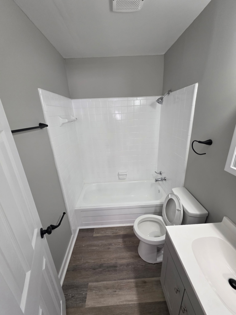 Clean bathtub and shower with updated vanity and modern fixtures in a 1 bedroom apartment at Mill Gardens Apartments in Warner Robins