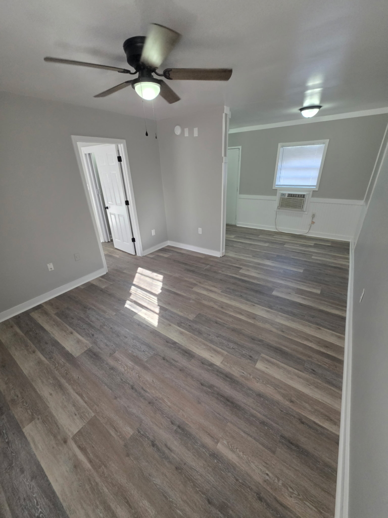 Spacious living room with wood style flooring and ceiling fan in a 1 bedroom apartment at Mill Gardens in Warner Robins Georgia