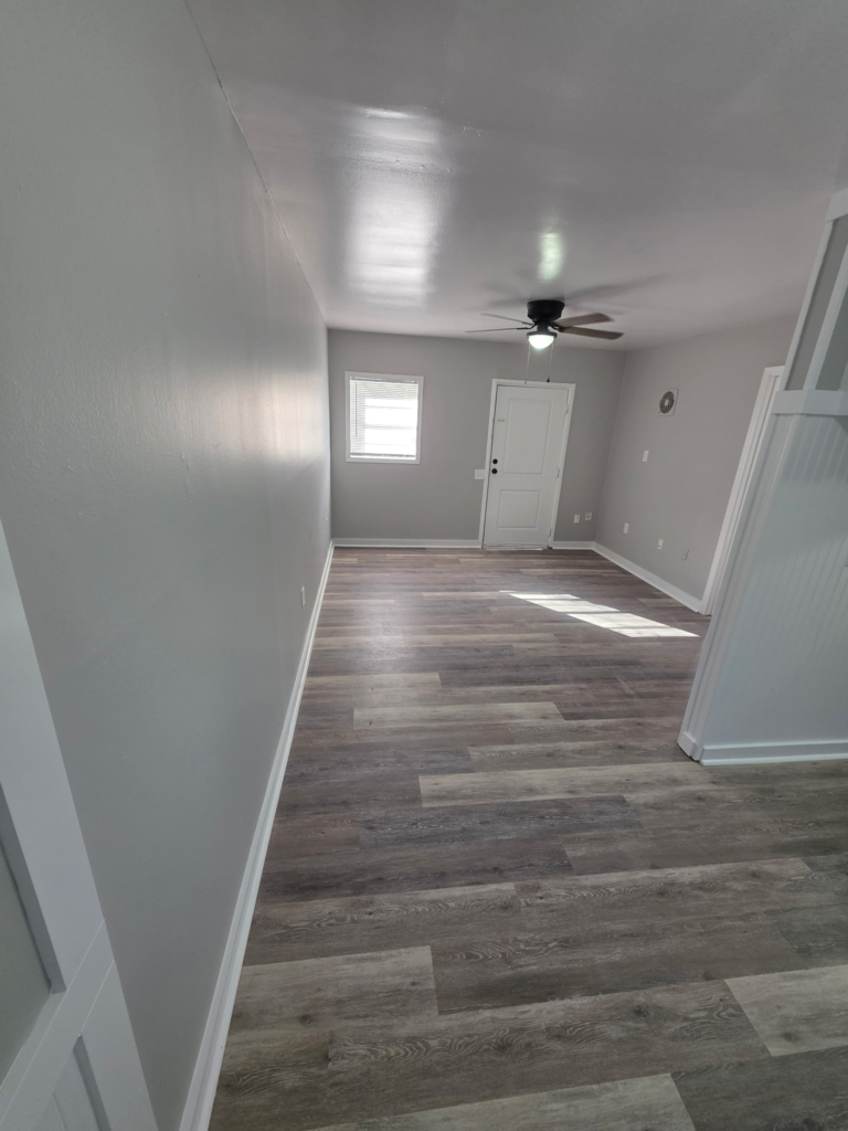 Open concept living area with wood look floors and ceiling fan in a 1 bedroom apartment at Mill Gardens Apartments Warner Robins GA